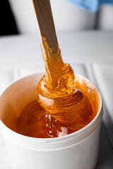 Transparent paste for sugaring or wax honey with a wooden spatula in sugar paste