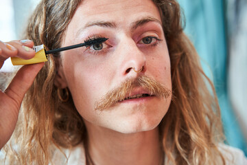 Portrait view of the trendy gay man with moustaches applying mascara