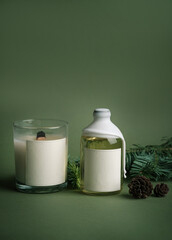 A mockup of aromatic diffuser and candles with an empty label for the product logo. Template for designers on green