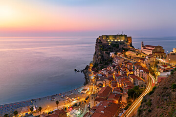 The city of Scilla Calabria Italy. Elevated view of the illuminated Ruffo castle at sunset - obrazy, fototapety, plakaty
