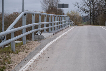 Fototapeta na wymiar new bridge over the river Vircava in Latvia countryside. Asphalt road, Steel safety railing.