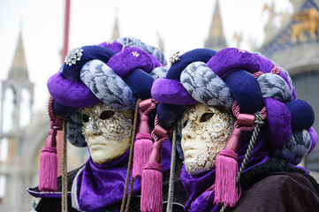 Carnival in Venice, Italy. Two masks in turbans at St Mark's Square  (St Mark's Basilica at background) during traditional Carnival.