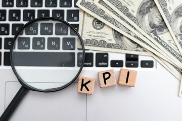 KPI ( Key Performance Indicator) - acronym on wooden cubes on the background of a cactus and banknotes. Business concept