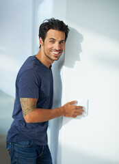 Man, wall and light switch in home bedroom or portrait smile for weekend, calm peace of holiday...