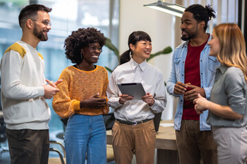 Multiethnic colleagues standing together and talking about work in their modern office.