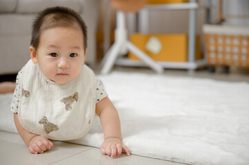 Asian baby boy Crawling on the carpeted floor in the living room and baby looking at the camera and playing alone in the room at home.