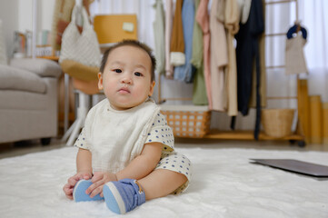 A little Asian boy crawled on the floor in the living room. A baby is playing in the children's room of the house.