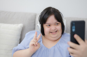 A disabled young woman with Down syndrome goes on social media and uses her mobile phone to take...