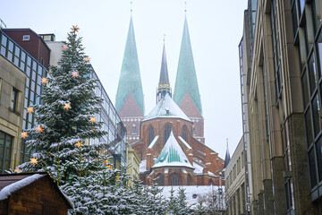 Fir trees with shining stars at the Christmas market behind the Marienkirche (meaning St. Mary church) on a snowy winter day in Lubeck, Germany, copy space