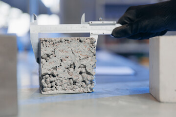 Worker engineer measures and controls quality of concrete cube in laboratory. Concept industry lab...