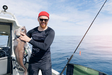 Deep sea sport fishing on yacht in ocean. Happy Male fisherman holding grenadier big fish,...