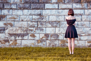 The young girl hugged her arms around his waist and looks at the stone wall. - 692623127