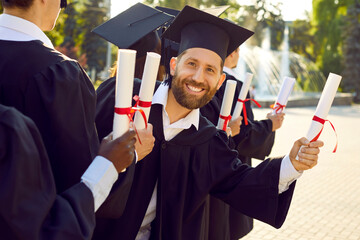 Photo of university or college student at outdoor graduation event Happy young man in black cap and...