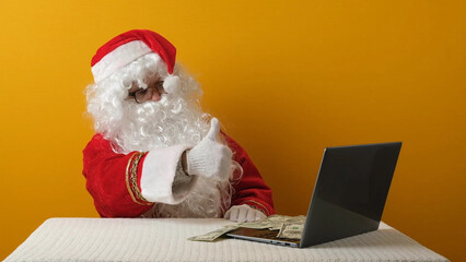 Santa Claus with money dollars and laptop.