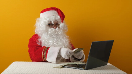 Santa Claus with money dollars and laptop.