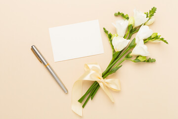 White fresia flower with empty paper on color background, top view