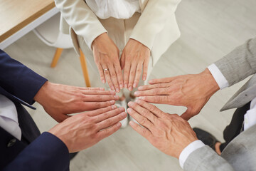 Three business partners put their hands together as symbol of unity, motivation and cooperation....
