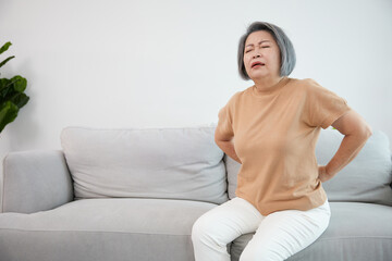 Obraz premium senior woman suffering from back pain on sofa
