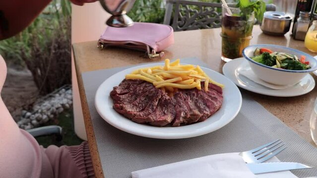 mujer hecha salsa verde sobre un plato con carne y patatas