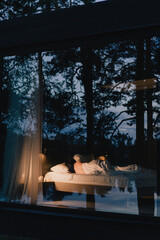 Bedroom in apartment or house with reflection in window glass of night forest.
