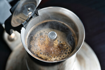 Traditional Italian-style coffee with the Moka, freshly brewed hot coffee produces foam and steam.

