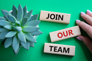 Join our team symbol. Wooden blocks with words Join our team. Beautiful green background with...