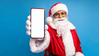 Image of hands of santa claus holding tablet with blank screen and copy space on blue background