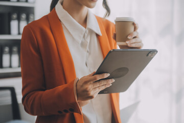 Portrait of Young Asian woman hand freelancer is working her job on computer tablet in modern office. Doing accounting analysis report real estate investment data, Financial and tax systems concept.