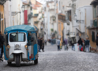 Small Blue and White Vehicle Driving Down a Street - tuk-tuk