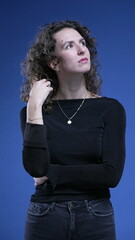 Pensive woman plays with hair while pondering decision, daydreaming vertical video of 20s person in...