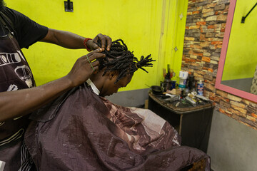 A barber fixes his client's braids inside his barbershop