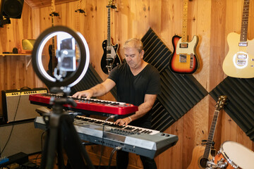 Man playing on synthesizer and recording video in studio