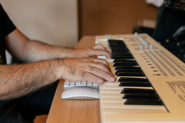 Crop unrecognizable male keyboardist playing synthesizer in studio