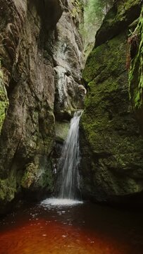 Waterfall in the rocks in the national park of Adrspach-Teplice Rocks, Czech Republic. Vertical video 4k
