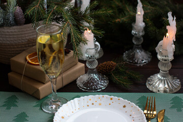 New Year's table setting with a glass of champagne. Preparations for the New Year and Christmas, Christmas tree and romantic candles