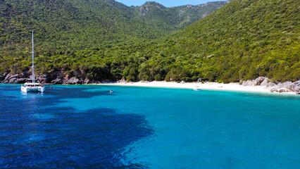 Sailing boat and catamaran in Greece; Crystal water, beautiful colors and shades of blue. In the background the island