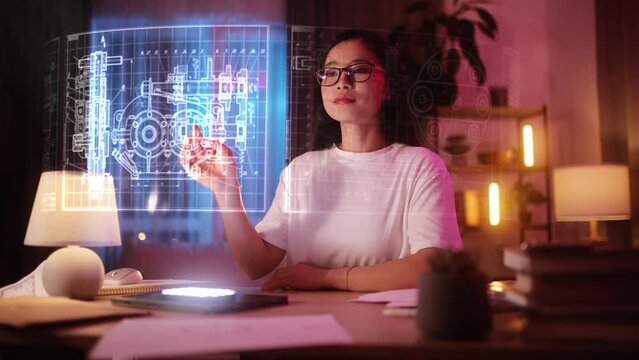 A young Asian woman is working on a technical product using a hologram. A woman engineer works at home with technical drawings