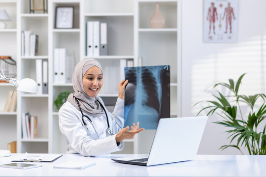 A female doctor in a hijab conducts an online appointment on a laptop, shows x-rays, consults a patient.