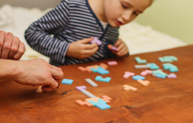 board logic games puzzles on the table and the child plays with them selective focus