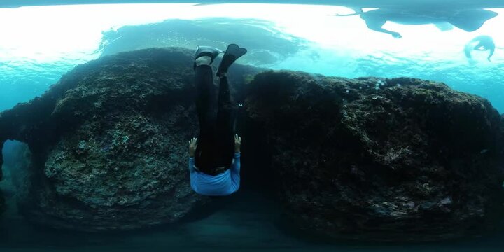 Spherical VR 360 degrees footage of the freedivers diving into the cave and swimming through it and surface inside the cavern