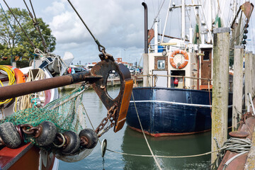 Traditional old german fishing cutter boats moored Neuharlingersiel harbor Wadden sea East Frisia Northern Germany. Commercial fish crab shrimp trawler beam trawl nets North Sea small port city - obrazy, fototapety, plakaty