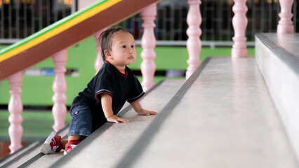 Little baby boy climbing up stairs.1 year old adorable Asian toddler development. Kid danger and...