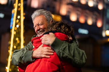 Embraced little boy and his grandfather enjoying the Christmas fair during winter holidays.