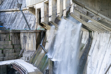 Hydroelectric power plant. Water stream flows from concrete dam gates. Renewable and alternative...