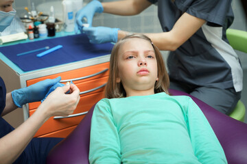 Little scared girl sitting in chair in dentist doctor office. Kid,child afraid of tooth extraction,...