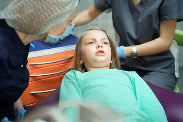 Little scared girl sitting in chair in dentist doctor office. Kid,child afraid of tooth extraction,...