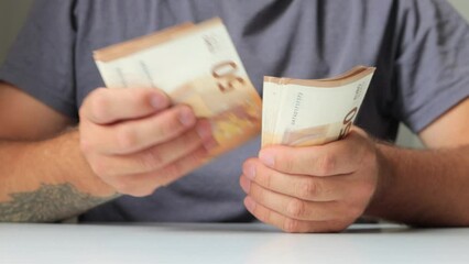 Close-up of a businessmans hands counting euro bills at a table - Powered by Adobe