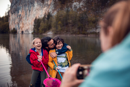 Mother taking picture of father and children while fishing in nature