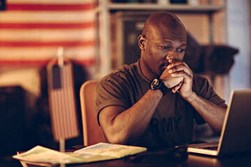 Young US marine soldier working on laptop in military base