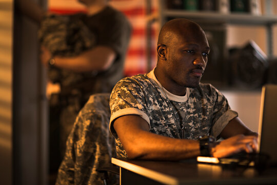 Young US marine soldier working on laptop in military base